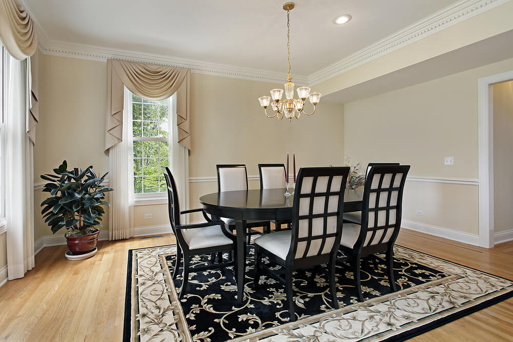 Formal dining room with very light beige walls, white ceiling and trim and light wood floor. Black dining table with six black and white dining chairs match the black, beige and white rug Formal dining room with very light beige walls, white ceiling and trim and light wood floor. Black dining table with six black and white dining chairs match the black, beige and white rug