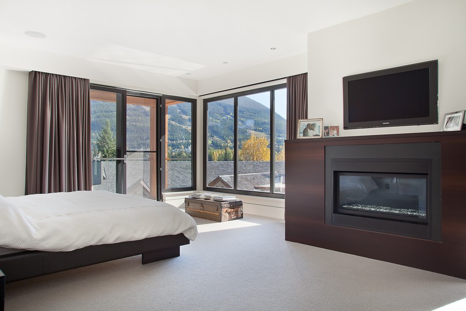 Wide Bed and White Quilt near Black Fireplace