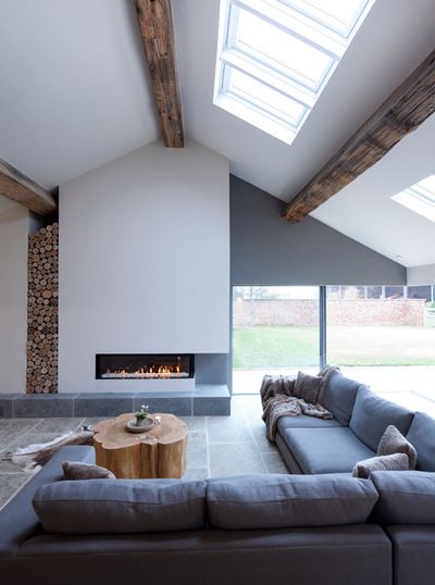 Simple, gorgeous living room with high ceilings, exposed wooden beams, built-in fireplace and open windows