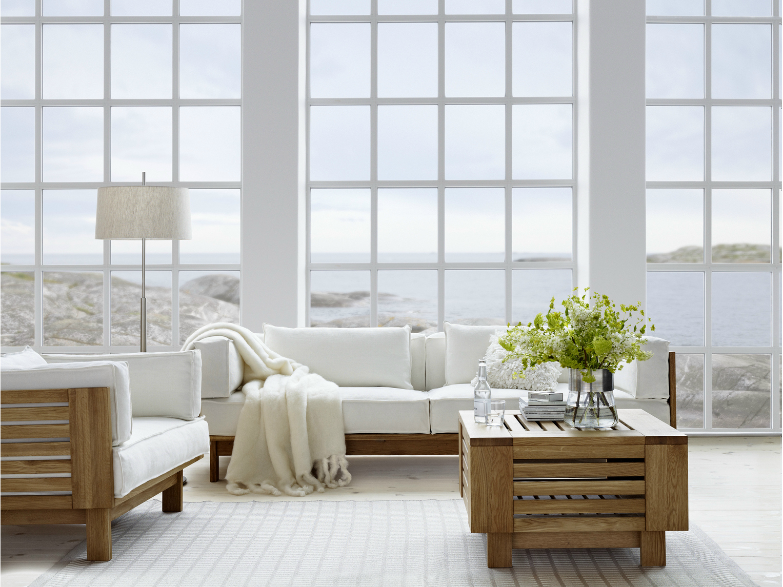 Living area with Large Bay Windows From Floor To Ceiling and decorated with curve sofa, an arm chair, and a square table