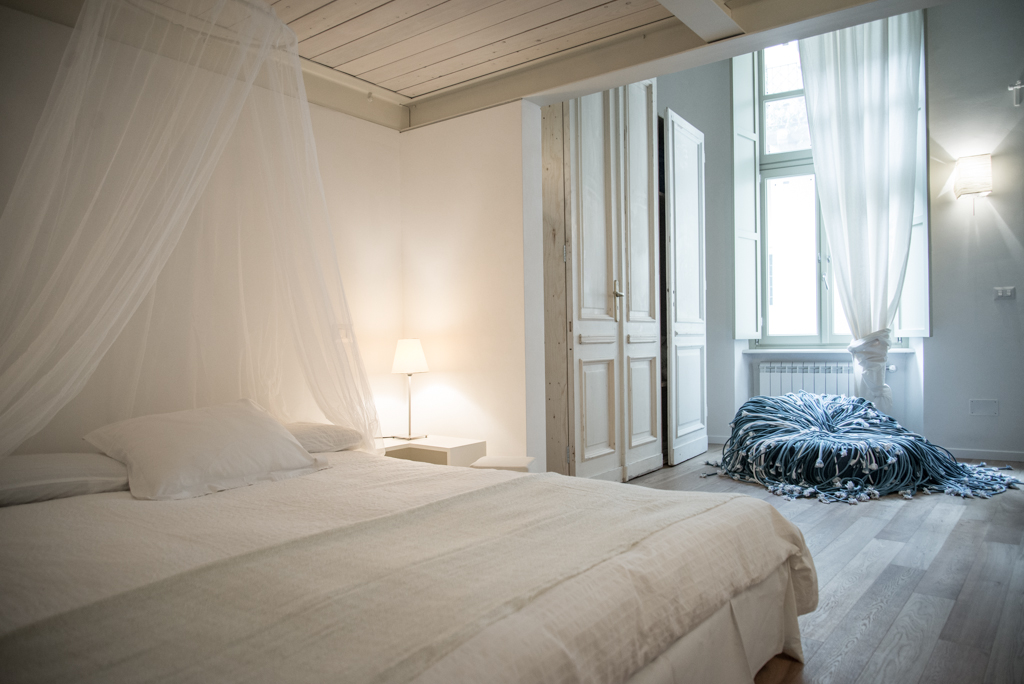 Via delle Orfane by CON3STUDIO - Small Pillows On Bed Added Near Glass Windows On Wall Decor Via delle Orfane by CON3STUDIO - Small Pillows On Bed Added Near Glass Windows On Wall Decor